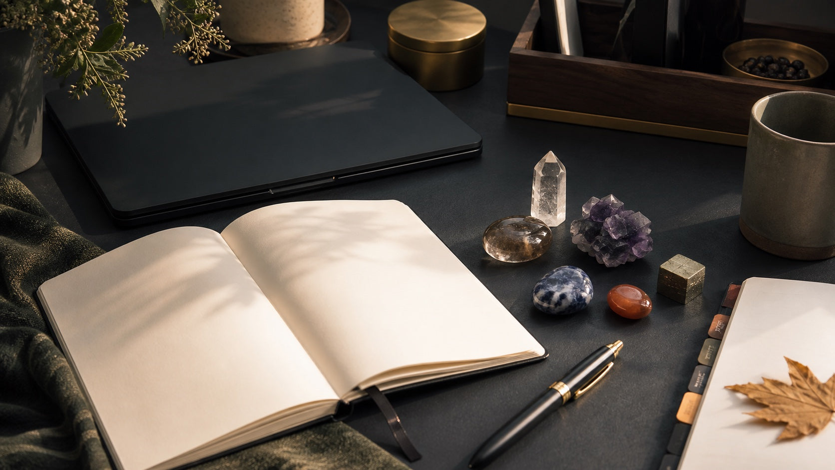 Editorial desk with notebook, laptop, clear quartz, smoky quartz, fluorite, sodalite, carnelian, and pyrite arranged as symbolic intention anchors for study and work