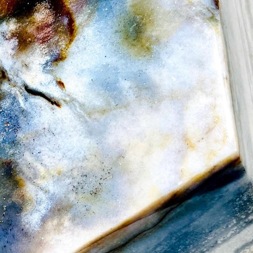 Close-up of pale mineral texture, inclusions, and a dark band on Silver Leaf Jasper AE105