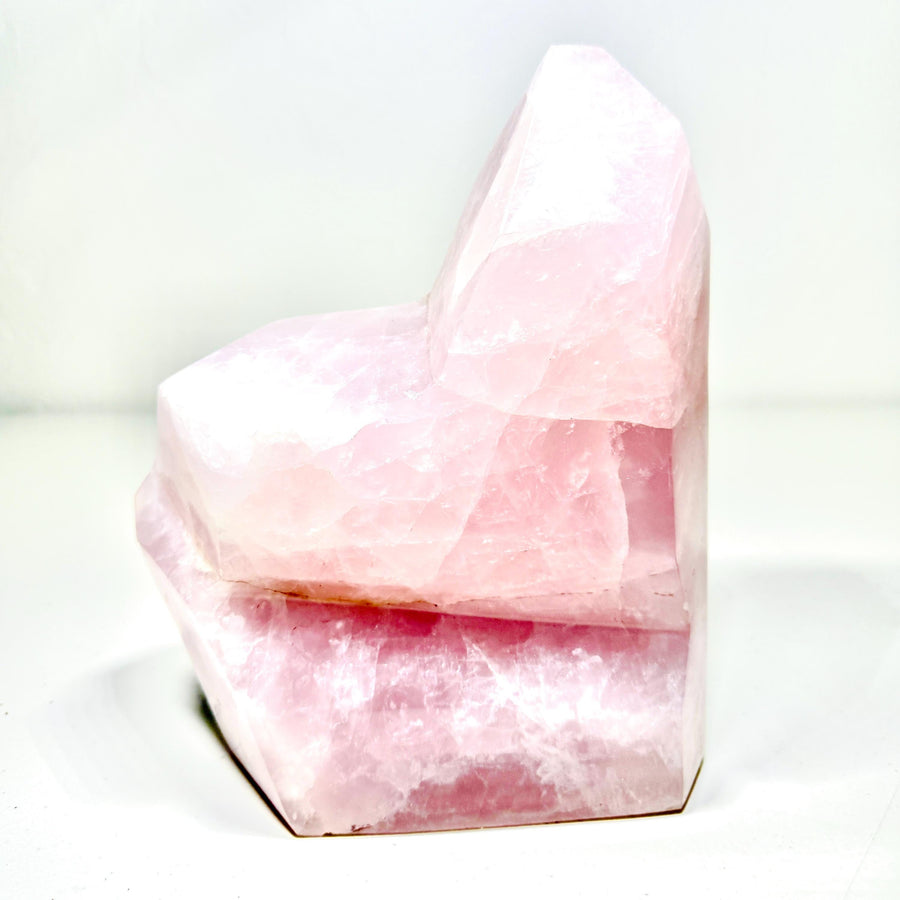 Large soft-pink rose quartz geometric sculpture with angular facets and natural clouding